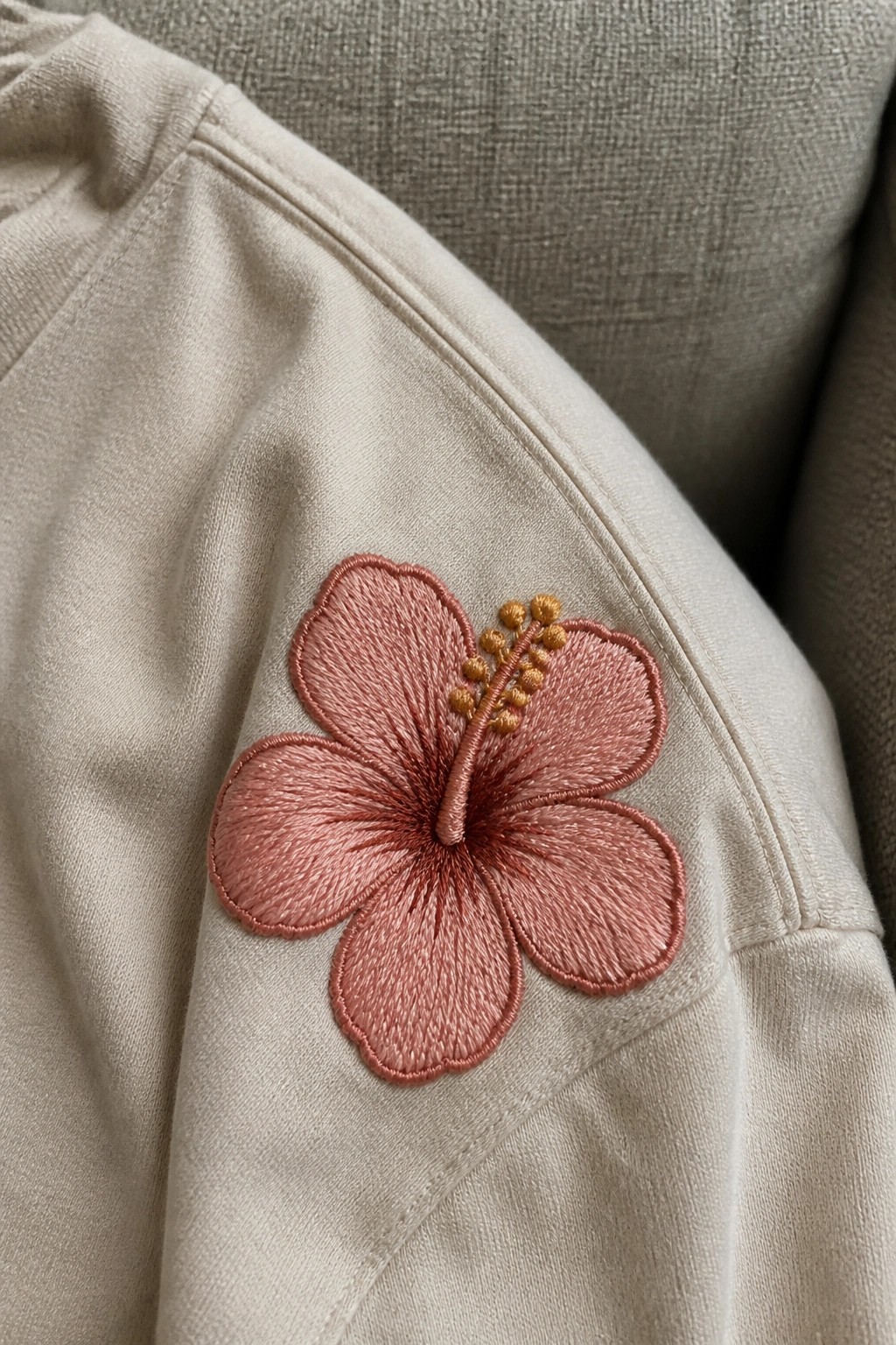 Pink hibiscus flower embroidered on beige sweatshirt sleeve