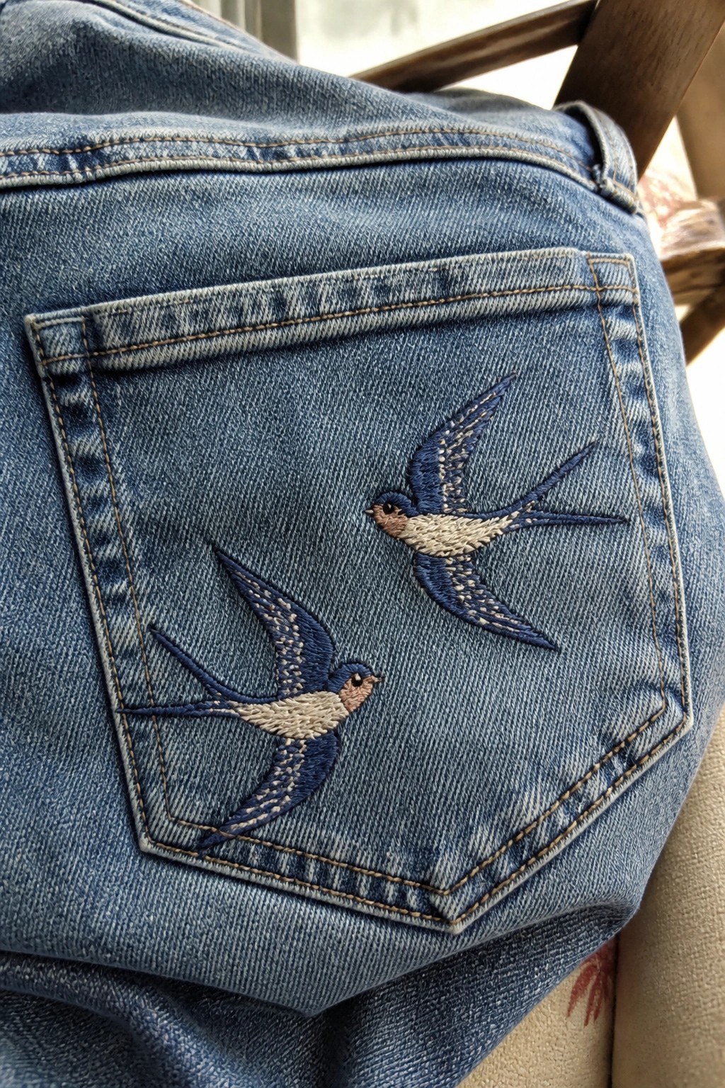 Blue denim jeans back pocket with two embroidered blue and white swallows