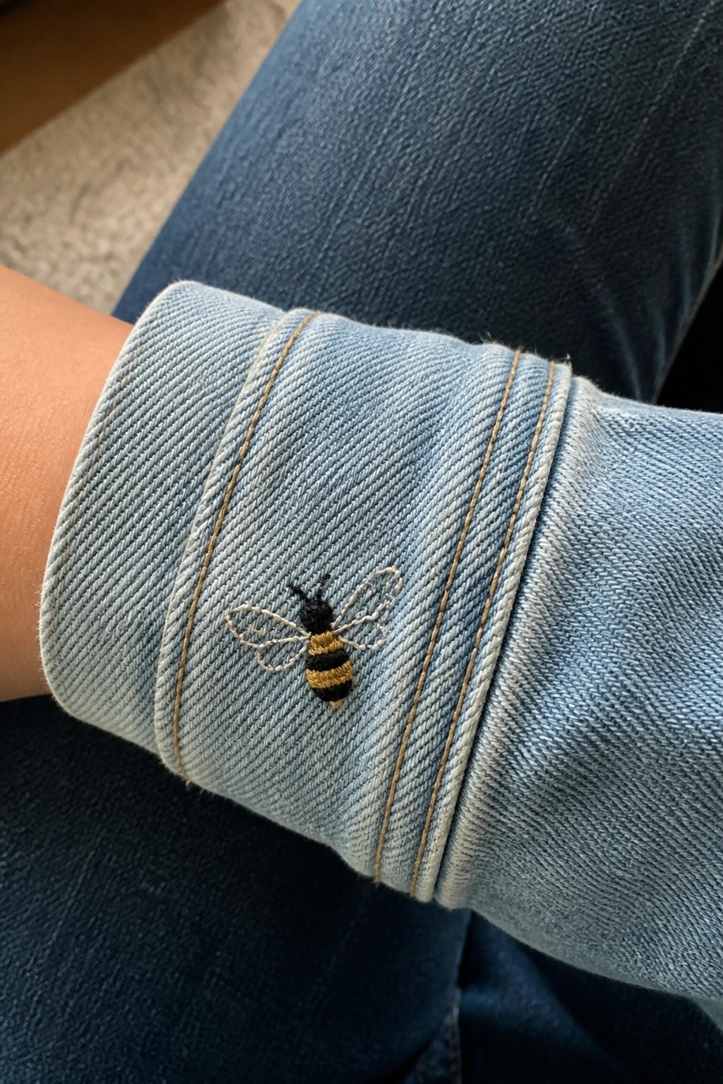 Embroidered black and yellow bee on cuff of light blue denim jacket
