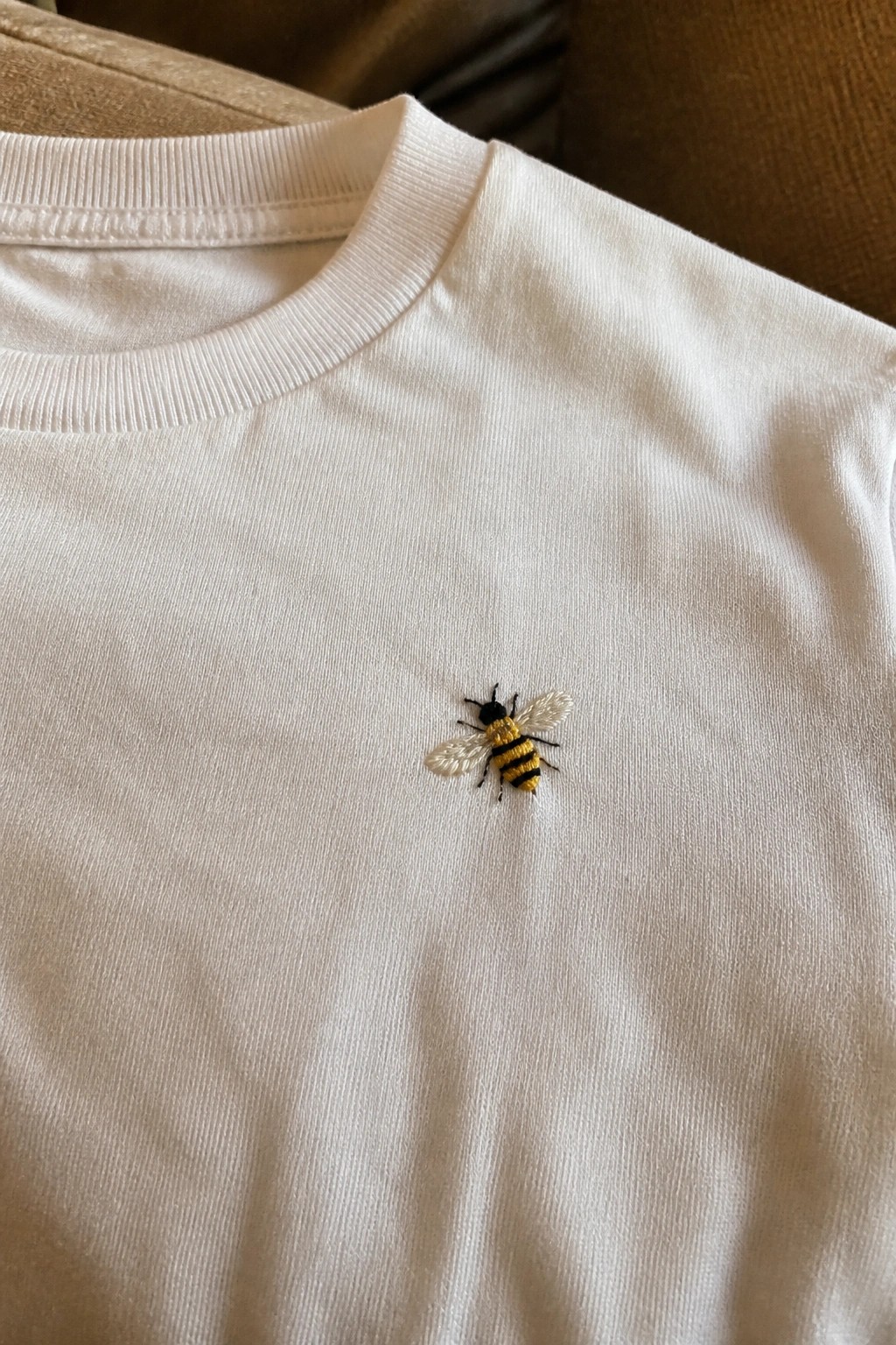 White crewneck t-shirt with yellow and black embroidered bee on chest