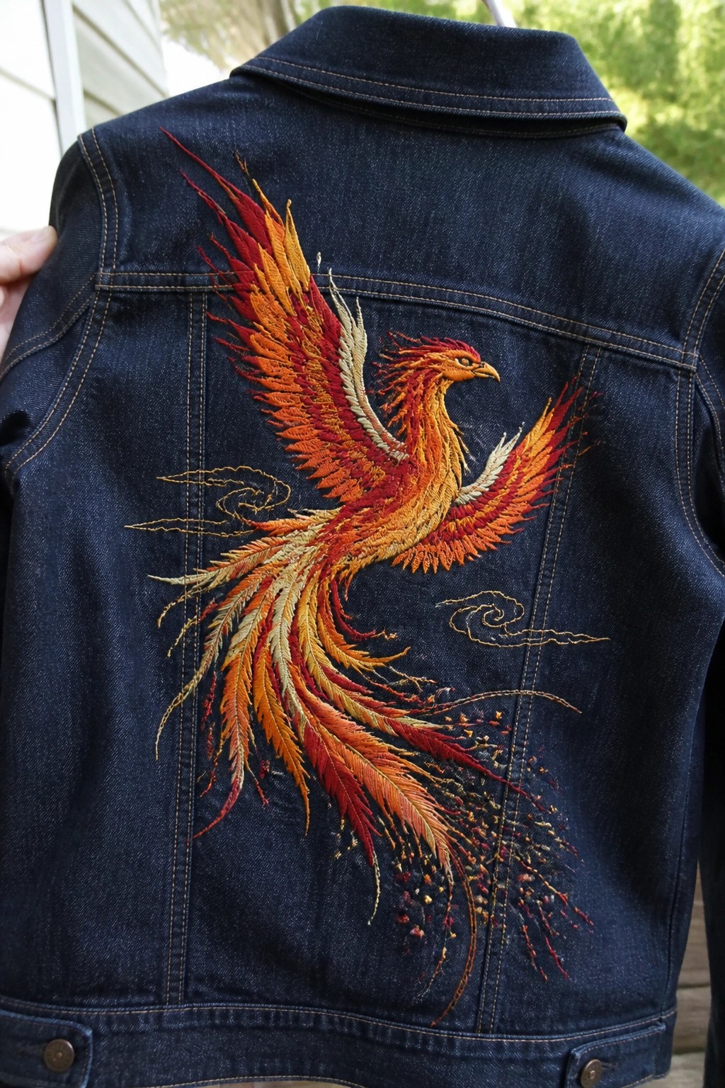 Dark denim jacket back with vibrant embroidered phoenix in red and orange tones