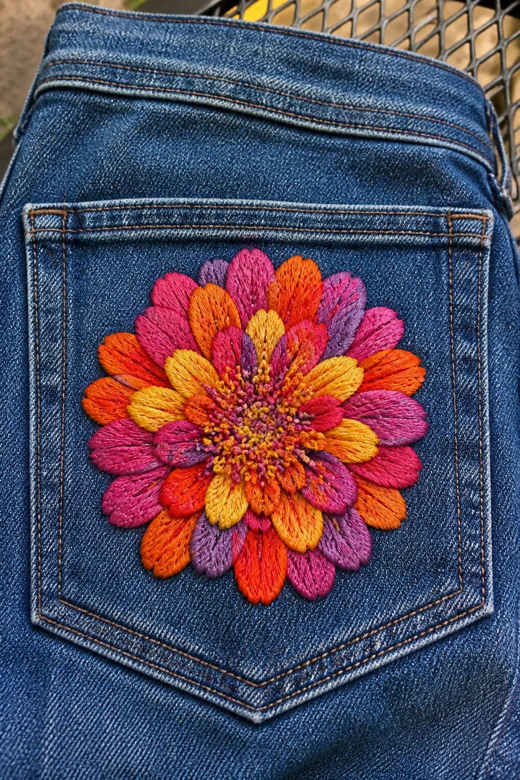 Blue denim back pocket with vibrant multicolored floral embroidery.