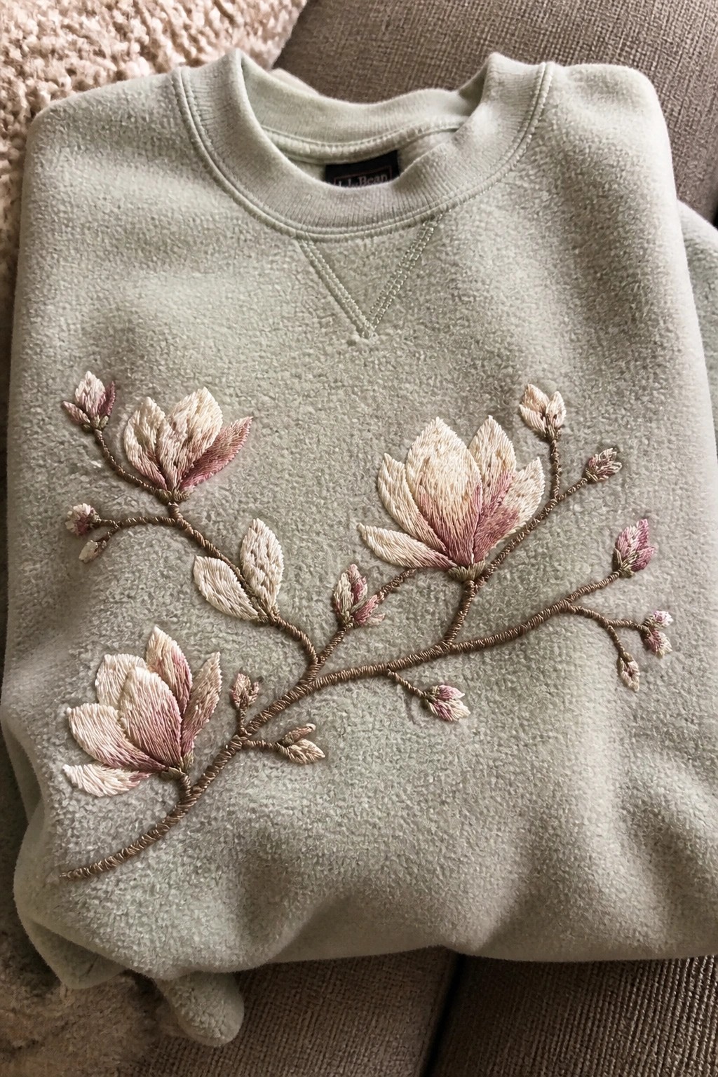 Light green sweatshirt with embroidered pink and cream flower branches across the front.