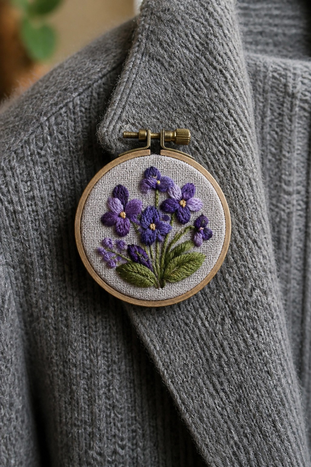 Purple flower embroidery in a hoop on gray knit sweater