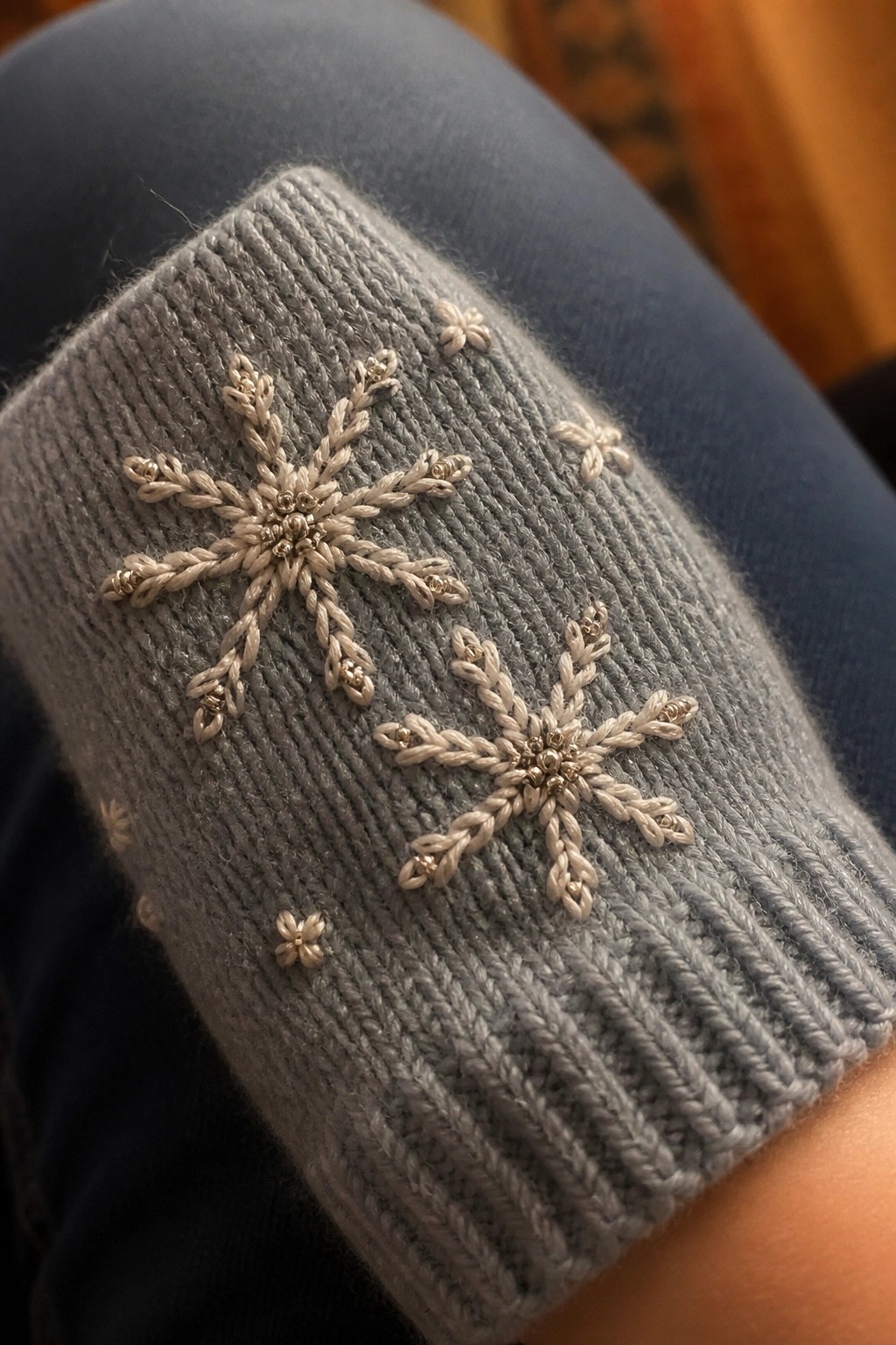 Gray ribbed knit cuff with embroidered white snowflakes and beaded accents.