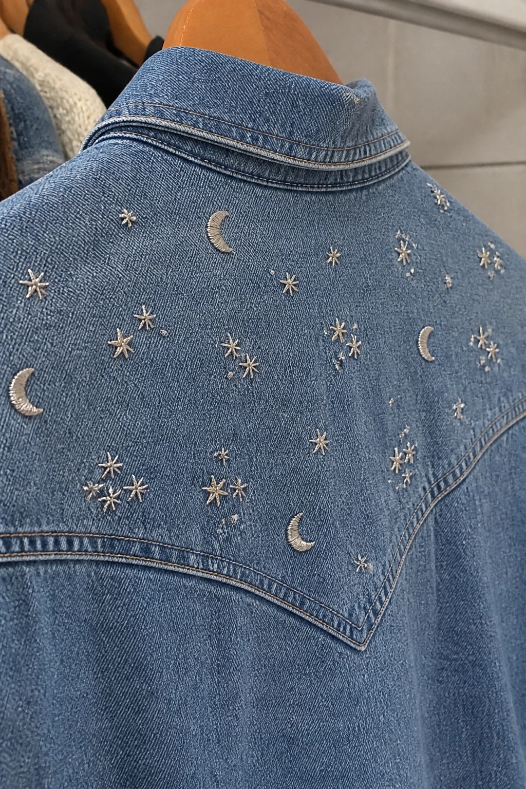 Blue denim jacket with silver embroidered stars and crescent moons on shoulders