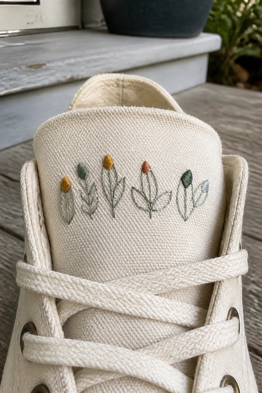 White canvas sneaker with delicate embroidered flowers in muted colors on toe.