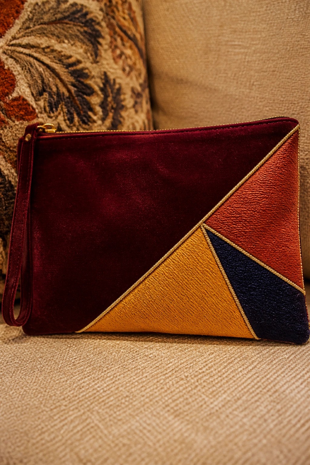 Maroon velvet geometric clutch with orange, yellow, and navy panels plus gold trim.