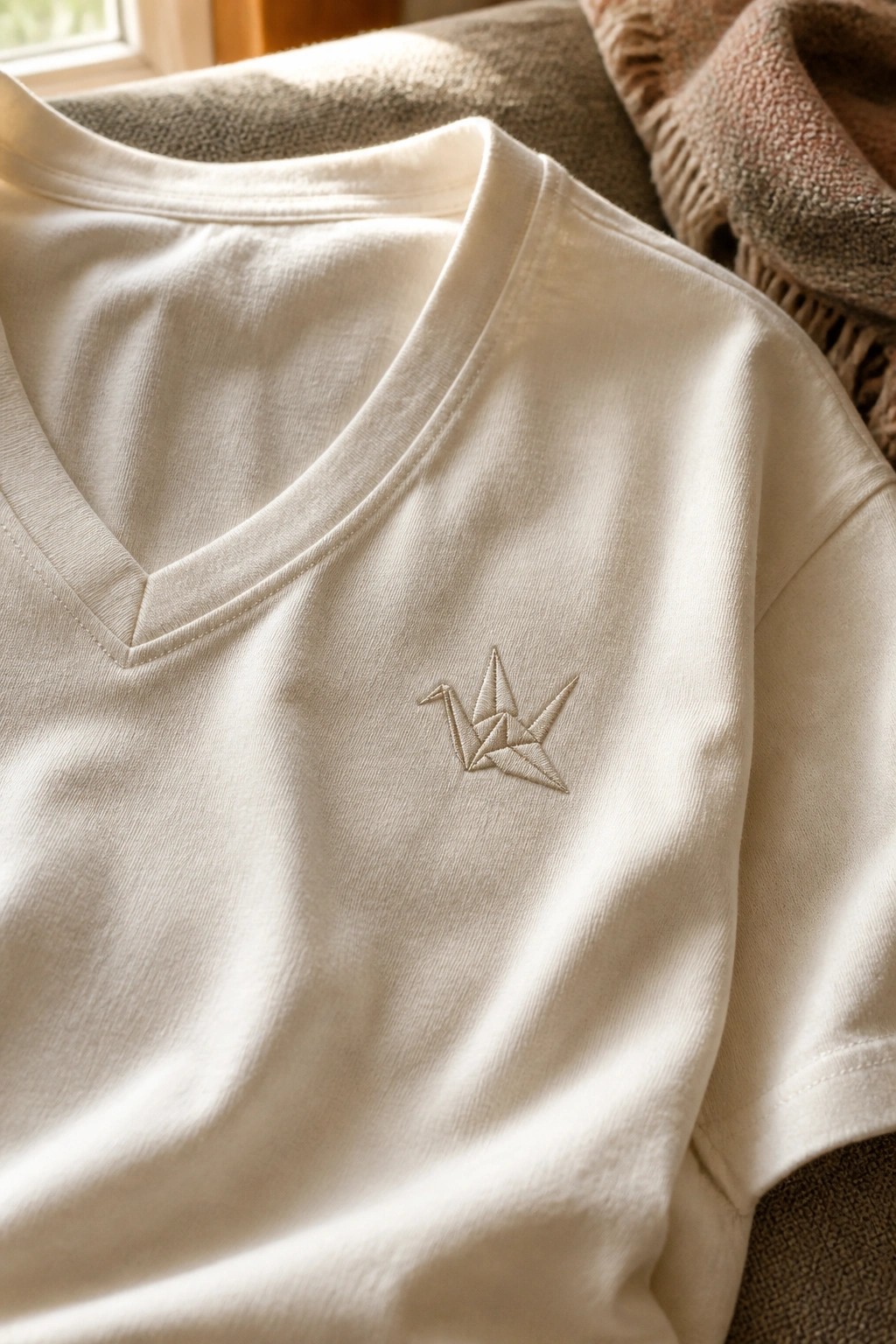 Cream V-neck t-shirt with delicate embroidered origami crane on the chest.