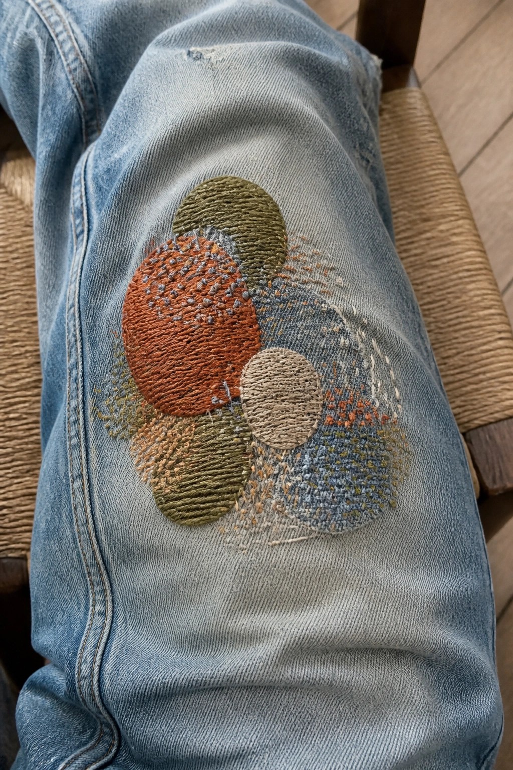Light blue denim jeans with colorful embroidered circles on the knee