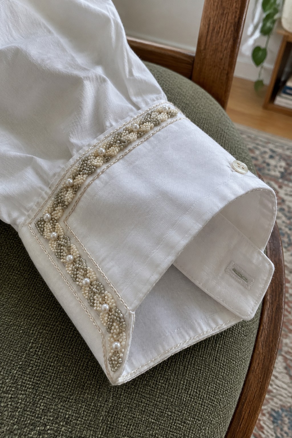 White shirt cuff with a narrow border of clustered beads and larger pearls.
