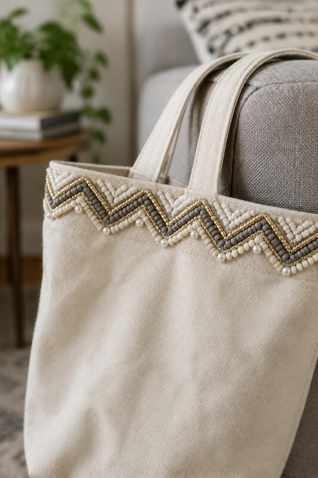 A cream canvas tote with a white, gray, and gold beaded chevron border along its top edge.