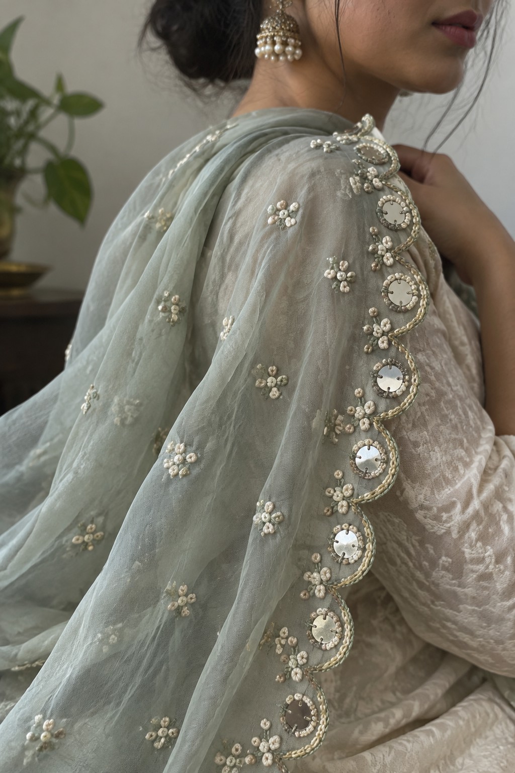 A pale sheer dupatta with a scalloped embroidered border, reflective circular accents, and scattered cream floral motifs.