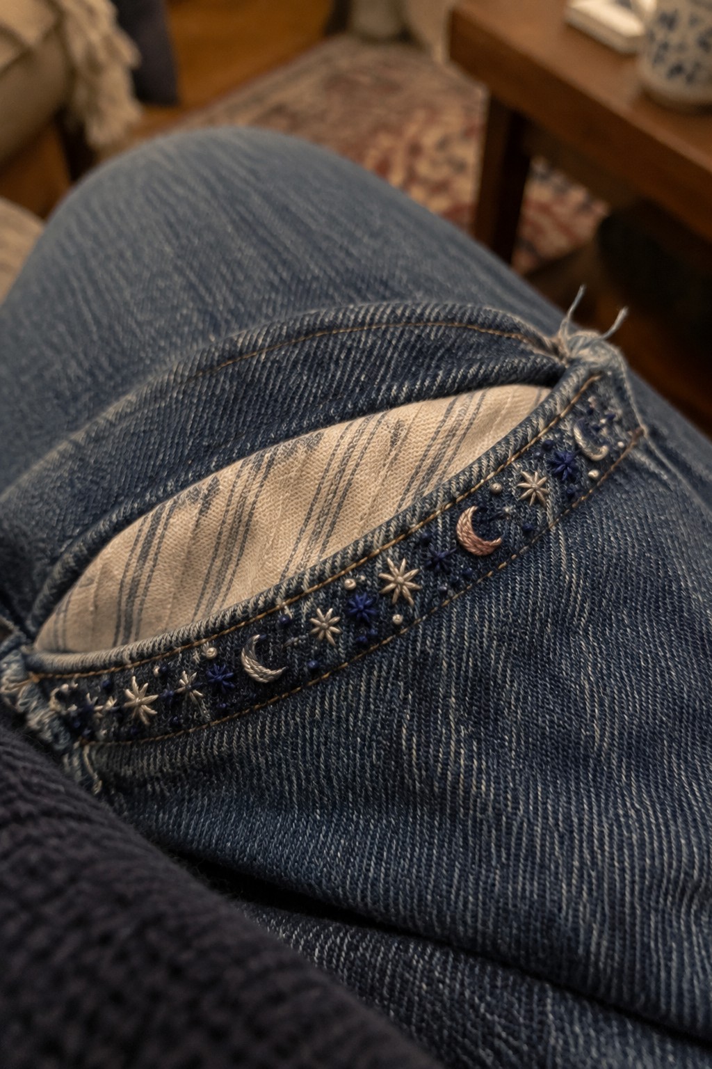 Close-up of jeans with crescent moons and starbursts embroidered along the waistband.