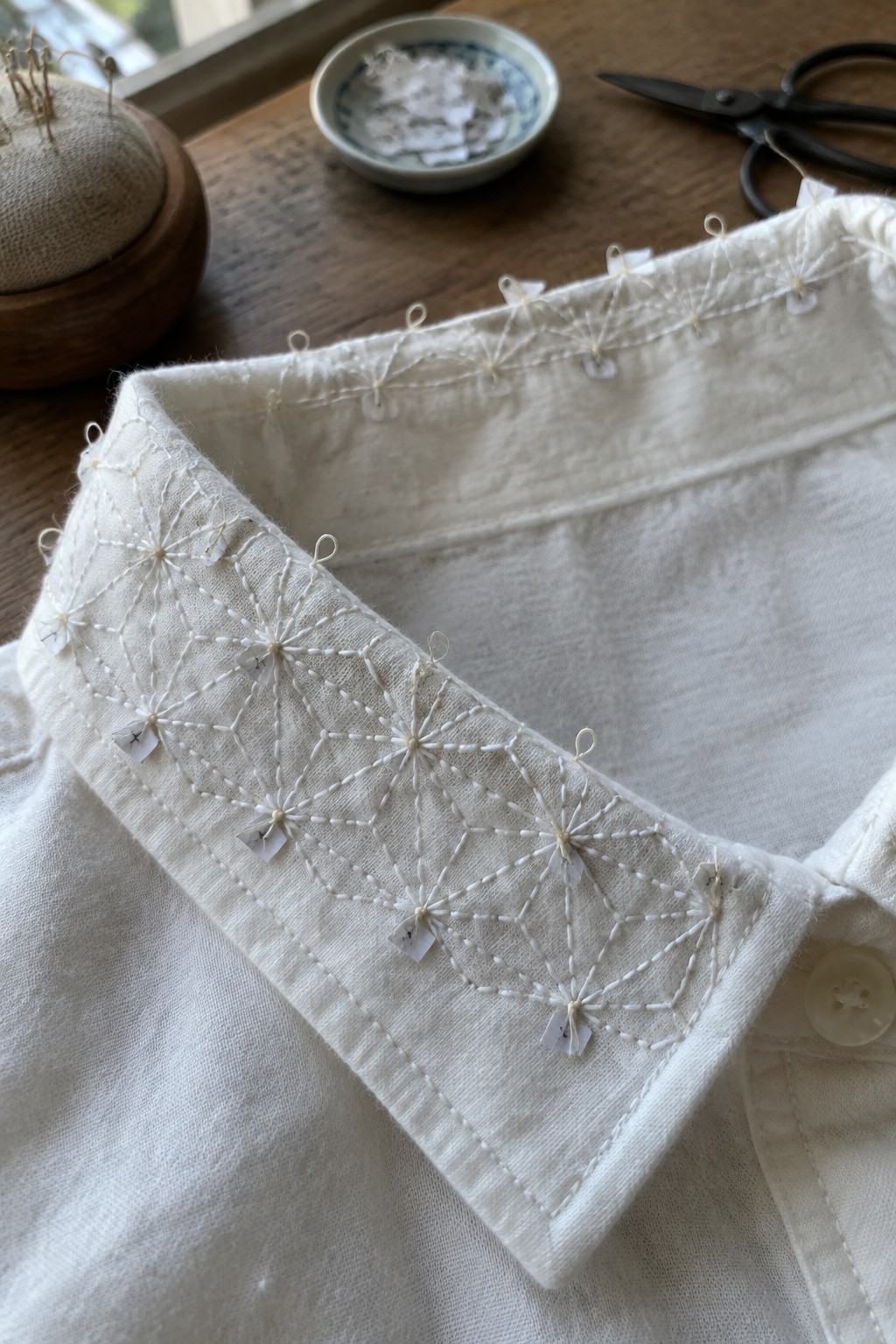 White geometric embroidery decorates the collar of a light-colored shirt.