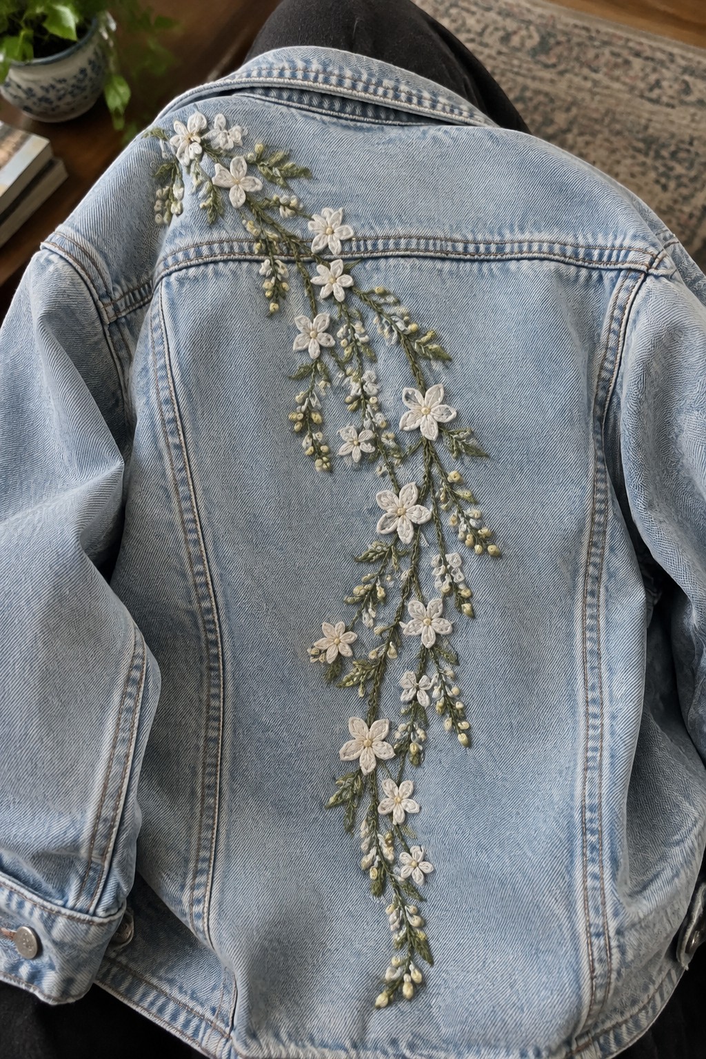 A light blue denim jacket with a raised white blossom vine embroidered down the back.