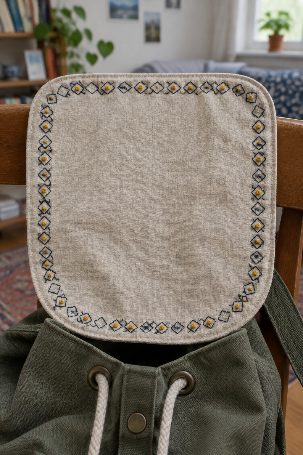 A cream backpack flap has a border of dark outlined diamonds with small yellow accents.