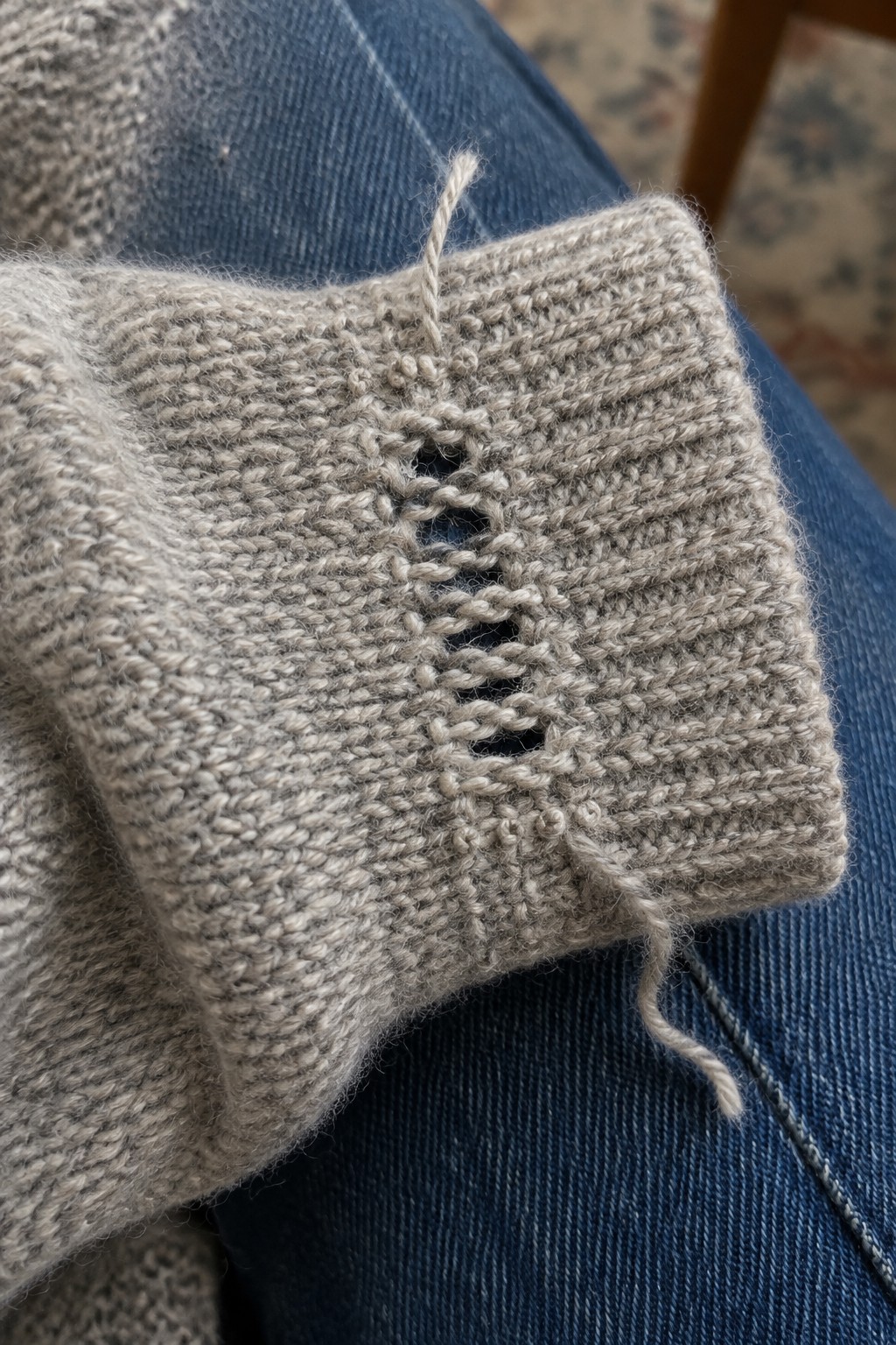 A beige knitted cuff has a vertical opening laced closed with yarn.