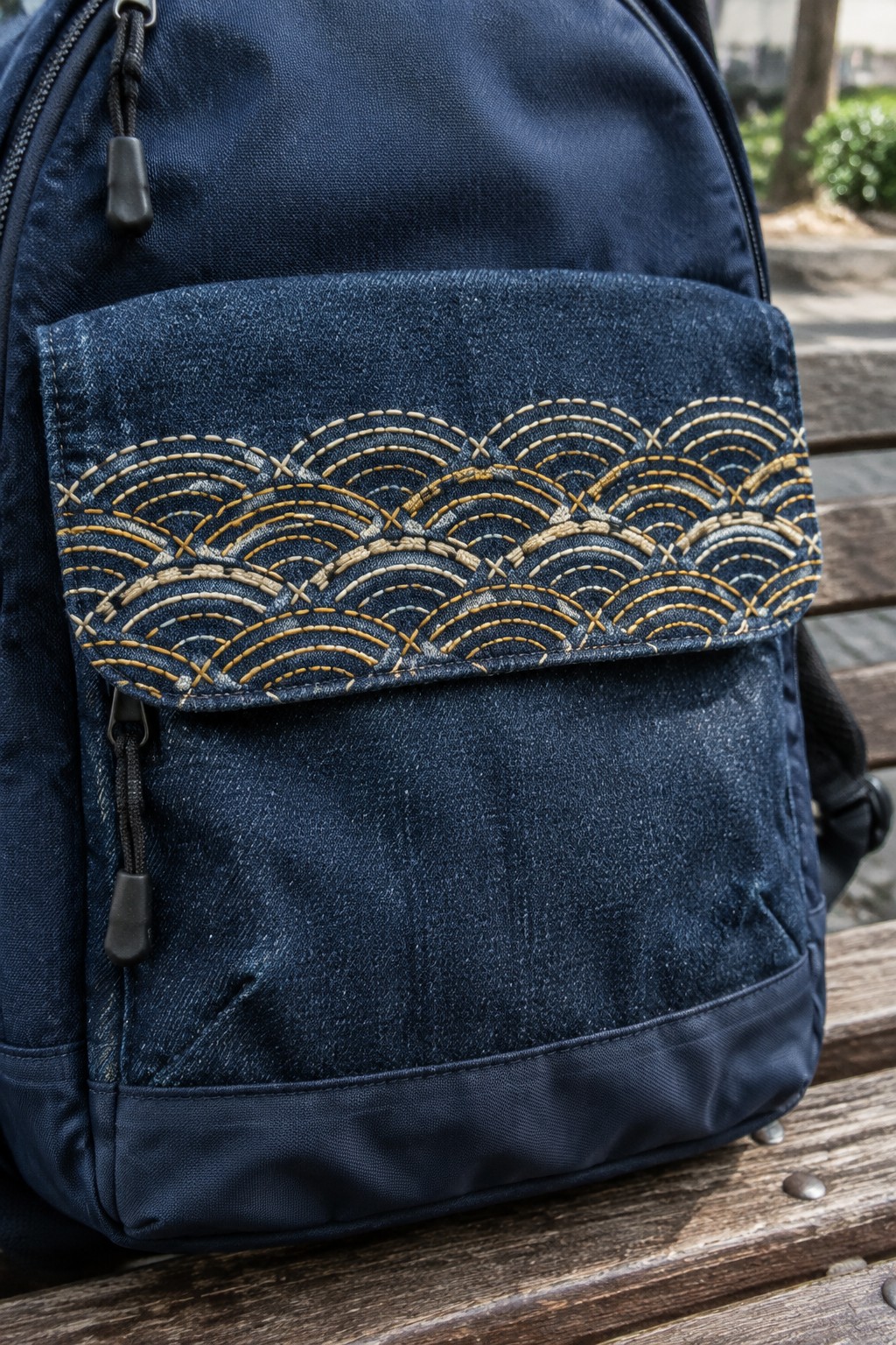 A navy fabric backpack with cream and gold Seigaiha wave embroidery across its front flap.